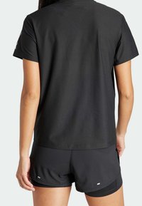 Svart sporttröja med texturerad yta, korta ärmar och avslappnad passform, kombinerad med matchande svarta shorts med en liten logotypdetalj.