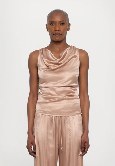 Haut en satin à col drapé en rose pâle, ajusté à la taille, avec une texture lisse et un drapé élégant. Accompagné d'un pantalon large plissé de la même couleur.