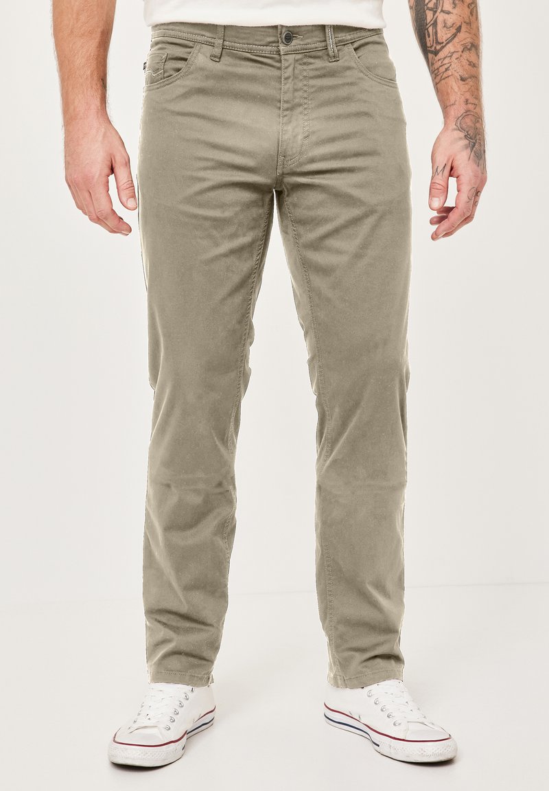 Khaki chinos made of cotton, featuring a straight leg, five pockets, and a button closure, paired with white sneakers.