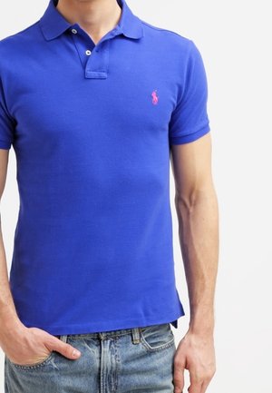 Polo bleu en coton respirant avec un logo rose contrastant sur la poitrine. Col classique et manches courtes, avec un ourlet droit.