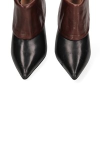 Puntige enkelboots met een zwarte leren onderkant en een bruine leren manchet. Gladde textuur met een glanzende afwerking.