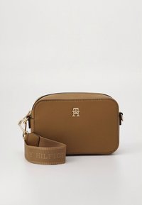 Brown leather crossbody bag with gold hardware, rectangular shape, zippered closure, and a detachable strap featuring embossed text.