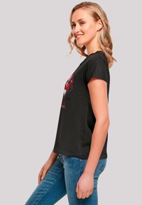Black T-shirt with short sleeves, featuring a colorful heart graphic and text on the front. Fabric is smooth and lightweight.