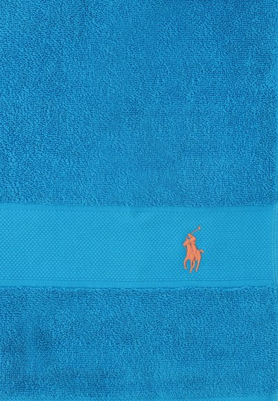 Serviette texturée bleue avec une bande tissée ornée d'un joueur de polo orange brodé à cheval tenant un maillet.