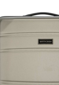 Wittchen suitcase in light beige color, textured surface, horizontal ridges, and a black logo plate. Features a sturdy top handle.
