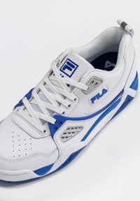 Baltas sporta apģērbs ar ziliem akcentiem, sieta paneļiem, apaļu purngalu un perforētu dekoru. Iekļauj šnerves un logo uz sāna.