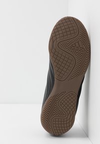 Czarna podeszwa sportowego buta z teksturowanym wzorem i brązowym gumowym uchwytem. Z logo Adidas wkomponowanym w design.