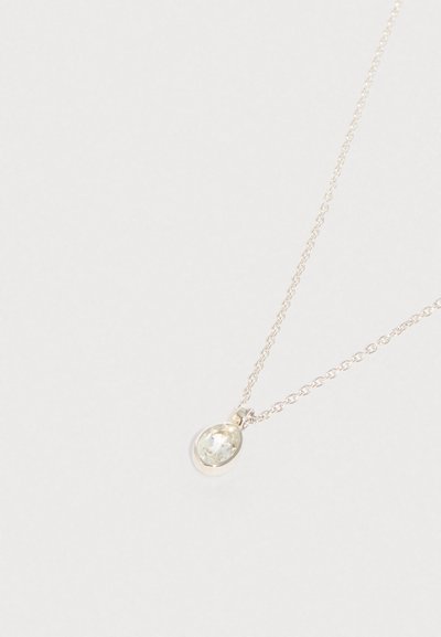 Jemný stříbrný náhrdelník s malým oválným přívěskem z průhledného kamene na světlém pozadí.