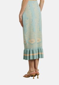 Strickbleistiftrock in Hellblau mit beigen Blumenmustern, mit einem gerafften Saum und horizontalen Streifenakzenten. Lässige Passform.