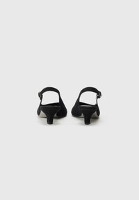 Scarpe con tacco slingback in suede nero con punta arrotondata e tacco basso. Presentano una cinturino regolabile con dettaglio fibbia metallica.