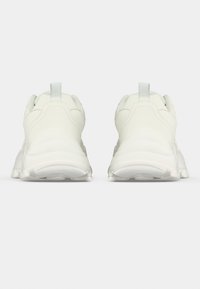 Λευκά αθλητικά παπούτσια με επάνω μέρος από απαλό δέρμα, επενδυμένο κολάρο και υφασμένο καουτσούκ στη σόλα. Διαθέτουν ταινία τράβηγματος στο πίσω μέρος και στρογγυλεμένο σχέδιο.