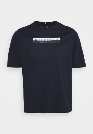 Camiseta de algodón azul marino con mangas cortas. Presenta un estampado gráfico en el frente que incluye el logo "HILFIGER" con un acento azul.