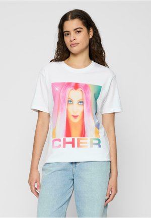 White cotton t-shirt featuring a colorful graphic print of a person with long, pink hair and the text "CHER" in gradient letters below.