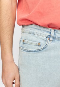 Lichtblauwe denim jeans met een klassiek recht model. Beschikt over een voorzak, subtiele slijtage en metalen hardwareaccenten.