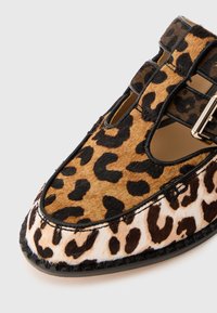 Pantofi cu imprimeu de leopard, realizati dintr-un amestec de blana sintetică maro și bej, având un detaliu negru, un design cu decupaje și o brelată cu cataramă metalică.