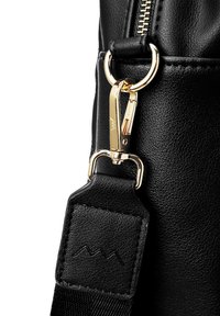 Detail einer schwarzen Ledertasche mit einem goldenen Reißverschluss, Karabinerhardware und einem strukturierten Riemen mit Logo-Prägung auf einem rechteckigen Patch.