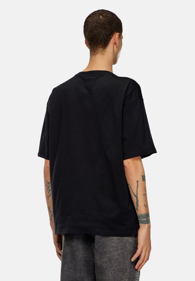 Черен oversized памучен тишърт с кръгло деколте. Къси ръкави и свободен кройка, с детайли от шевове. Без видими логота.
