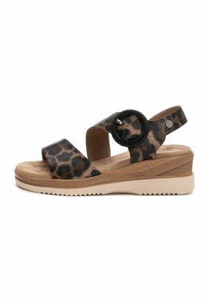 Sandalias de estampado de leopardo con tiras anchas, un acento circular negro y un tacón de cuña con un diseño marrón texturizado y una suela beige.