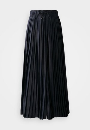 Črna naborka krilo iz gladkega materiala. Ima elastični pas z vrvicami. Segajo do sredine tele z enotnimi vertikalnimi naborki.