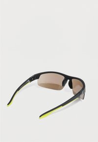 Αθλητικά γυαλιά ηλίου με μαύρο πλαίσιο και κίτρινες λεπτομέρειες, ελαφρύ σχέδιο, καφέ σκουρόχρωμους φακούς και ελαστικά άγκιστρα στα αυτιά για άνεση.