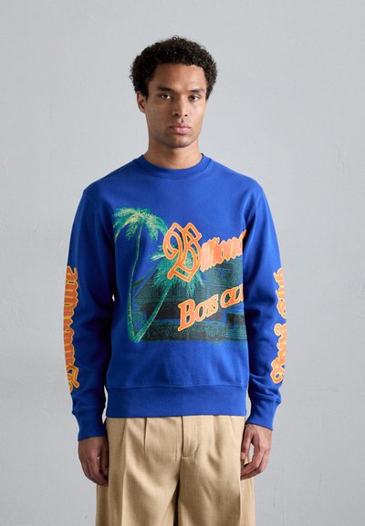 Sweatshirt bleu avec impression graphique représentant des palmiers et le texte "Billionaire Boys Club" en orange, design texturé sur les manches.