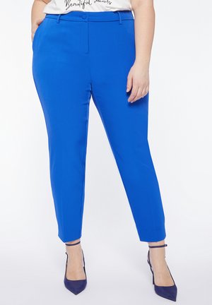 Pantaloni su misura blu con chiusura a bottoni, tasche laterali e vestibilità slim, abbinati a tacchi a spillo coordinati. Tessuto liscio e uniforme.