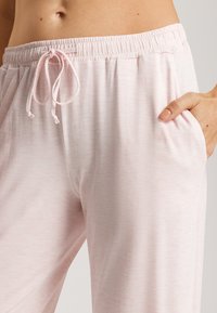 Lichtroze, comfortabele loungebroek met een losse pasvorm, gemaakt van zachte stof, met een elastische tailleband met een trekkoord en zijzakken.