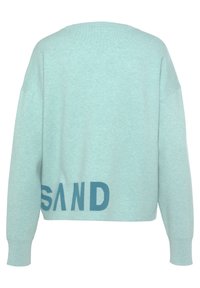 Mintgrüner Pullover mit lässigem Schnitt, überschnittenen Schultern und dem Wort "SAND" in dunkelblauer Schrift an der Unterseite. Weiche Textur.