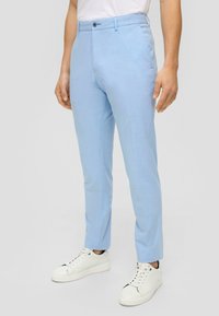 Světlomodré kalhoty v úzkém střihu, s plochým předním dílem a standardním pasem. Nošené s bílými teniskami, zdůrazňující čistý a moderní vzhled.