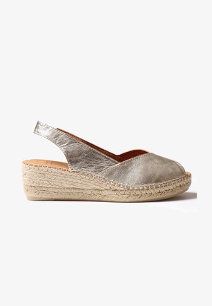 Metalizuotas sidabro espadrilio batelis su slingback dizainu, pintu juta platforma ir atvira nosimi. Lygus odinis viršus su siuvimo detalėmis.