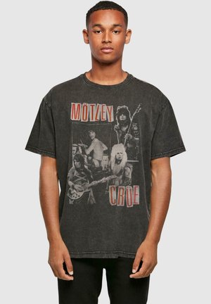 Black oversized t-shirt featuring a faded graphic of the band Mötley Crüe, with red text and a soft, worn texture. Short sleeves and crew neck.