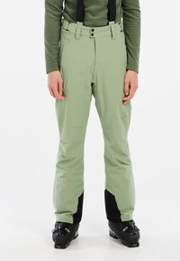 Pantalons de ski vert clair avec bretelles noires ajustables, fermeture éclair et pression, bas de jambe noir renforcé et genoux articulés pour la mobilité.