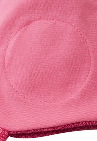 Różowy materiał o gładkiej teksturze z okrągłym akcentem wyhaftowanym na środku. Tkanina wydaje się miękka i lekko rozciągliwa.