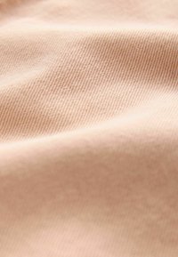 Mjukt rosa tyg med en subtil räfflad textur, som har en slät yta. Materialet verkar lätt och faller mjukt.