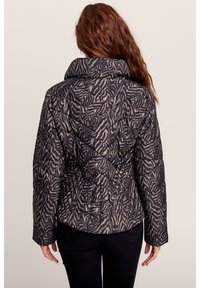 Steppjacke im schwarz-beigen Zebra-Muster, mit hohem Kragen und taillierter Silhouette, langen Ärmeln und strukturierter Oberfläche.