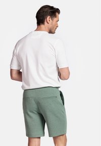 White short-sleeve shirt and green shorts with a textured finish, featuring two rear pockets and an adjustable waist tie.