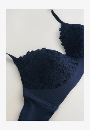 Marineblauwe bh met ingewikkelde kanten cups, gemêleerde stof band en verstelbare bandjes. Gladde textuur met decoratieve scalloped randen.