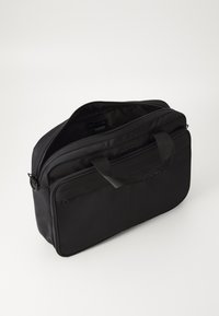 Sacoche pour ordinateur portable en nylon noir avec deux zips sur le dessus, une poche avant et des poignées robustes. Texture lisse et forme structurée pour un transport facile.