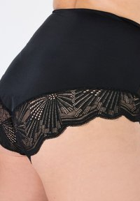Zwarte kanten slip met een gladde satijnen bovenkant en een gedetailleerde kantafwerking met een golvende rand. Het ontwerp bevat ingewikkelde patronen in de kant.