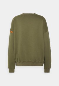 Olivgrön sweatshirt, bomullsmaterial, rundad hals, långa ärmar, ribbade muddar och nederkant, har en orange etikett på ärmen, slät textur.