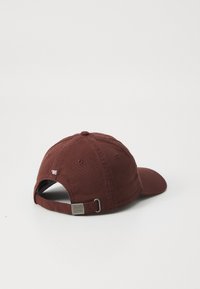 Căciulă de baseball maroon cu vizor curbat, textură din material textil, curea ajustabilă cu elemente metalice și broderie '85 aproape de spate.