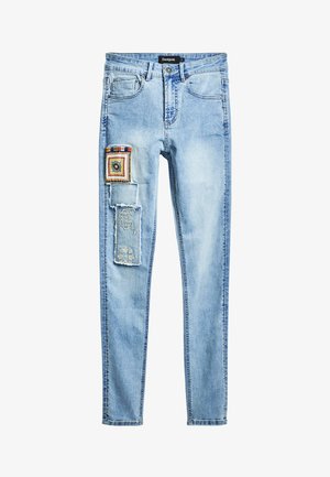 Ljust blå denimjeans med en figursydd design och dekorativa lappar samt broderi på vänster lår. Inkluderar standardfickor.