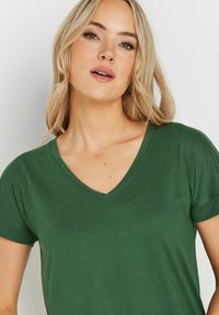Grön v-ringad t-shirt med korta ärmar, som har en mjuk textur och en avslappnad passform. Enkel design utan synliga mönster eller detaljer.