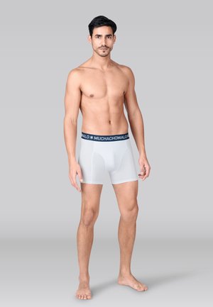 Biele boxerky s tmavomodrým pásom, na ktorom je biely nápis "MUCHACHOMALO". Hladká látka a priliehavý strih.