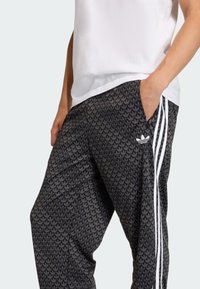 Μαύρα joggers με γεωμετρικό σχέδιο, με λευκές πλευρικές ρίγες και λογότυπο Adidas στον αριστερό μηρό.