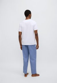 Hvit t-skjorte med korte ermer kombinert med lyseblå, løstsittende bukser. Antrekket har et enkelt design og mykt stoff.