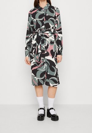 Sukienka koszulowa z długim rękawem w czarny, zielony i różowy kwiatowy wzór, z paskiem w talii, zaokrąglonym kołnierzem i zapinana na guziki z przodu. Do tego czarne buty.