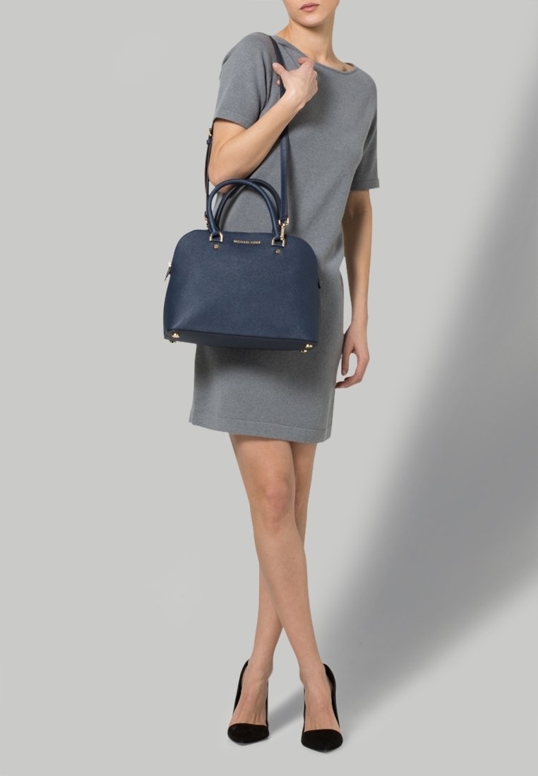 Borsa a mano in pelle blu navy con un design strutturato, hardware dorato, doppi manici arrotondati e tracolla removibile. Texture liscia.