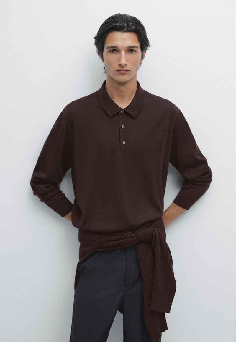 Bordeaux lange mouwen polo met een drie-knoopsluiting; ribbelstructuur; gecombineerd met donkere broeken en een gestructureerde trui om de taille.