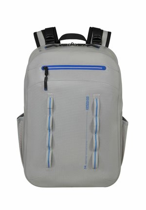 Sac à dos gris clair avec fermeture éclair bleue, double sangles verticales, bretelles rembourrées et poches latérales en mesh, conçu pour un usage quotidien.